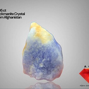 Könnte beinhalten: Ein roher Hackmanit-Kristall aus Afghanistan, 17,05 ct. Der Stein zeigt eine Mischung aus blauen, gelben und weißen Farbtönen. Das Bild enthält den Text "Hackmanite Crystal From Afghanistan".