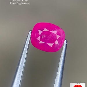Może przedstawiać: Żywy, fasetowany rubin w kolorze różowym, trzymany pęsetą. Klejnot ma wzór w kształcie gwiazdy na swojej powierzchni. Tekst na zdjęciu brzmi "0,45 ct Fasetowany Rubin z Afganistanu."