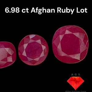Puede incluir: Tres piedras preciosas de rubí rojo, cada una con un corte facetado. Las piedras preciosas están dispuestas en una fila de izquierda a derecha, con la piedra preciosa más grande en el centro. Las piedras preciosas están sobre un fondo negro. El texto "6.98 ct Afghan Ruby Lot" está por encima de las piedras preciosas. El texto "AGS Afghan Gemstone Source" está debajo de las piedras preciosas.