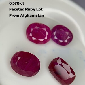Op de afbeelding: Een verzameling van vier gefacetteerde robijn edelstenen, met een totaal gewicht van 6,570 karaat, uit Afghanistan. De robijnen zijn dieprood van kleur en hebben verschillende ovale en rechthoekige vormen. De tekst luidt "Faceted Ruby Lot From Afghanistan."