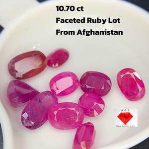 Puede incluir: Un conjunto de rubíes facetados de diversas formas ovaladas y rectangulares, presentados en un plato blanco. Los rubíes son de un color rojo-rosado vibrante. El texto en la imagen dice "10.70 ct Faceted Ruby Lot From Afghanistan."