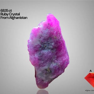 Puede incluir: Un vibrante cristal de rubí en bruto de Afganistán, con un peso de 68,15 ct. La gema muestra un rico tono rosado con áreas más claras y blancas. La imagen incluye el texto "68.15 ct Ruby Crystal From Afghanistan."