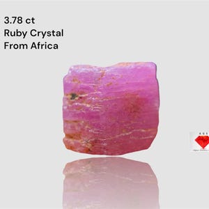 May include: A raw, pink ruby crystal from Africa, weighing 3.78 carats. The gemstone has a rough, textured surface and a natural, unpolished appearance. The image includes the text "3.78 ct Ruby Crystal From Africa".