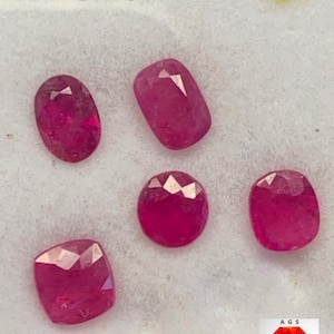 May include: Five faceted, deep pinkish-red rubies of varying shapes, including oval, cushion, and round cuts. The text 4.11 ct Afghan Ruby is visible in the top left corner, and an AGS Afghan Gemstone Source logo is in the bottom right.
