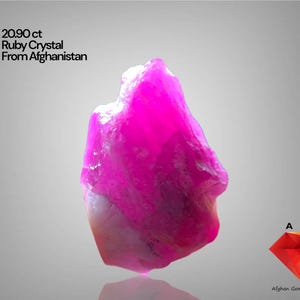 Puede incluir: Un vibrante cristal de rubí en bruto de Afganistán, con un peso de 20,90 quilates. La gema muestra un tono rosa brillante con una calidad translúcida. También incluye el texto "Ruby Crystal From Afghanistan".