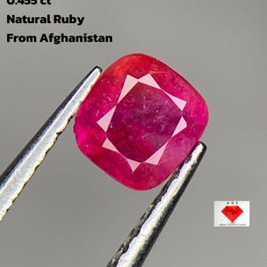 Può includere: Un rubino naturale taglio a cuscino dall'Afghanistan, tenuto da una pinzetta. La gemma è di un rosso vibrante con un interno sfaccettato. Il testo sull'immagine recita: 0,455 ct, Rubino naturale, Dall'Afghanistan.