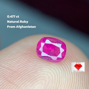 Può includere: Un rubino naturale sfaccettato dall'Afghanistan, del peso di 0,477 ct. La gemma è di un vivido colore rosso-rosato ed è esposta su uno sfondo neutro. Il testo sull'immagine recita "0.477 ct Natural Ruby From Afghanistan."