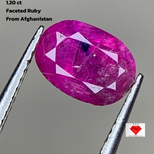 May include: A faceted ruby gemstone from Afghanistan, held by tweezers. The oval-shaped gem is a vibrant pink-red color, with visible facets. Text on the image reads: "1.20 ct Faceted Ruby From Afghanistan."