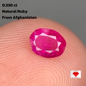 Op de afbeelding: Een natuurlijke robijn van 0,330 ct, afkomstig uit Afghanistan. De ovaal geslepen edelsteen heeft een heldere rozerode kleur en een gefacetteerd oppervlak. De tekst luidt: "0.330 ct Natural Ruby From Afghanistan."