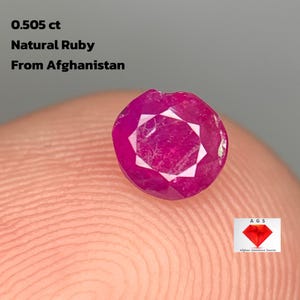 May include: A faceted, natural ruby gemstone from Afghanistan, weighing 0.505 ct. The gem is a deep, vibrant pinkish-red colour, with a geometric cut. The image includes the text "0.505 ct Natural Ruby From Afghanistan".
