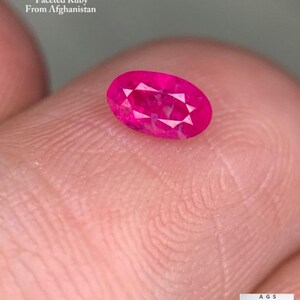 Puede incluir: Un rubí facetado de forma ovalada, de color rosa vibrante. La gema pesa 0,38 ct y es de Afganistán. La imagen también incluye el texto "0.38 ct Faceted Ruby From Afghanistan".