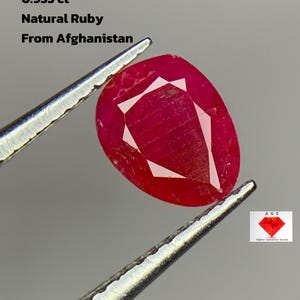 Puede incluir: Un rubí natural en forma de pera de Afganistán, sujeto con pinzas. La gema es de color rojo intenso con un interior facetado. Texto: 0,955 ct, Rubí natural, De Afganistán.