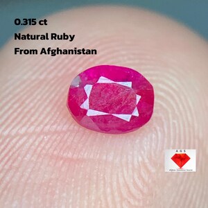 Puede incluir: Un rubí natural ovalado de 0,315 ct de Afganistán. La gema es de color rojo intenso con facetas internas. La imagen también incluye el texto "Natural Ruby From Afghanistan".