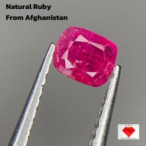 May include: A vibrant, natural ruby gemstone, weighing 0.280 ct, held by tweezers. The ruby is a deep pinkish-red color with visible facets. Text on the image reads "Natural Ruby From Afghanistan."