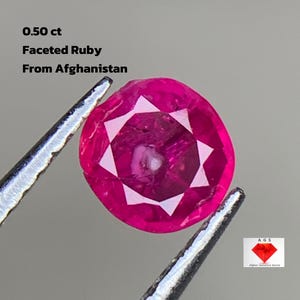 Op de afbeelding: Een gefacetteerde robijn, vastgehouden door een pincet, met een levendige roze tint. De tekst luidt "0,50 ct Faceted Ruby From Afghanistan". De edelsteen heeft een sterpatroon en een diepe, rijke kleur.