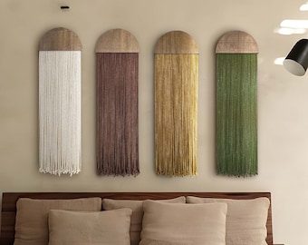 May include: Four wall hangings with a wooden half-circle top and long strands of yarn in white, brown, gold, and green.