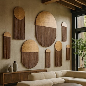 Może przedstawiać: Nowoczesny salon z beżową sofą narożną, okrągłym drewnianym stolikiem kawowym i okrągłym dywanem. Ściana zdobiona jest drewnianymi dziełami sztuki z półokrągłym wzorem i brązowymi frędzlami. Duże okno oferuje widok na zewnątrz.