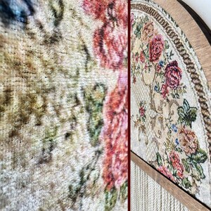 May include: A close-up of a beige and brown tapestry with a floral pattern. The tapestry is framed in a wooden frame and has a rope border.