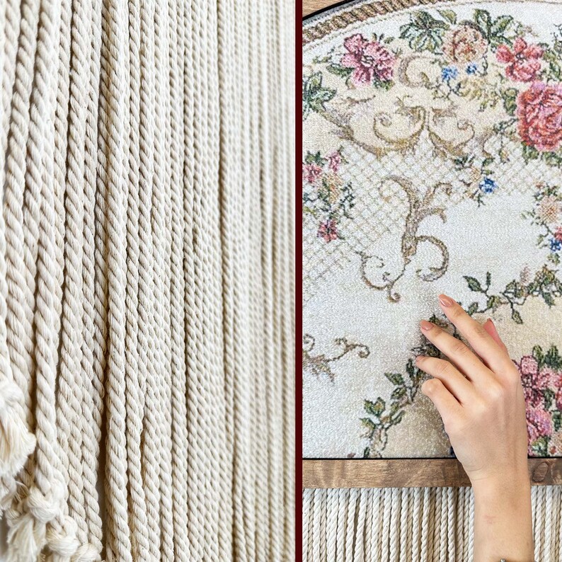 May include: A close-up of a white macrame wall hanging with a floral patterned rug hanging in the background.