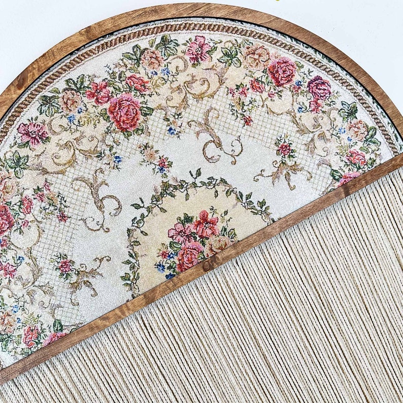 May include: A half-circle wooden frame with a floral tapestry design and a fringe of white yarn hanging from the bottom.