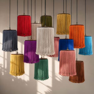 May include: A collection of pendant lamps with fringed shades in various colors, including red, purple, and blue. Each lamp has a cylindrical shade with a decorative fringe and a dark metal top.