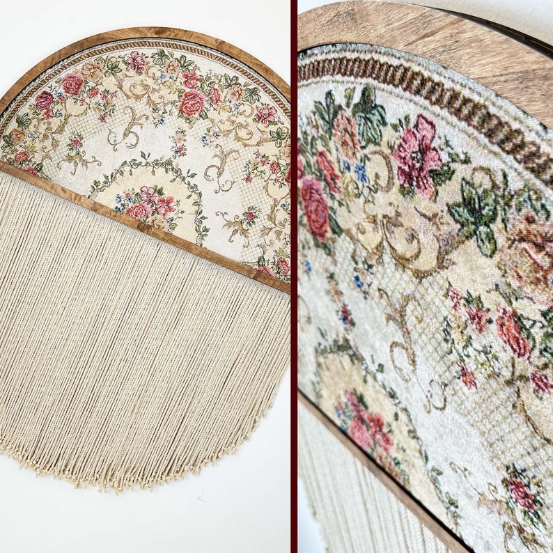 May include: A half-circle wall hanging with a floral patterned fabric framed in wood and a long fringe of white yarn.