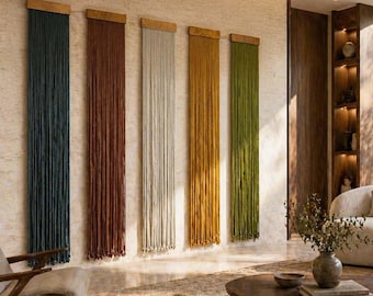Puede incluir: Cinco tapices de pared verticales en varios colores: verde azulado oscuro, marrón rojizo, blanquecino, amarillo dorado y verde oliva. Cada uno tiene una parte superior de madera y una franja de hilos colgantes. Están montados en una pared clara.