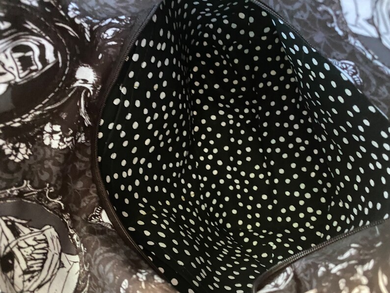 May include: Black and white polka dot fabric lining the inside of a bag. The fabric is smooth and has a subtle sheen.