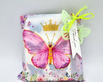 May include: A white gift bag with a pink butterfly design and a gold crown. The bag has a green ribbon and a white tag that says "Thank you".