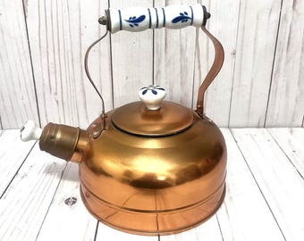 Tetera de cobre vintage con asa de cerámica de porcelana blanca y azul.