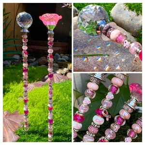 May include: Two pink and silver garden stakes with crystal tops and pink beads. The stakes are decorated with pink and silver beads, including pink ribbon charms. The stakes are on a bed of green moss.