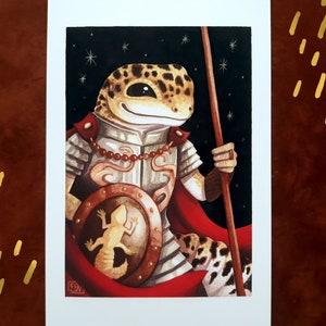 May include: A watercolor painting of a gecko wearing armor and holding a spear. The gecko is wearing a red cape and has a shield with a smaller gecko on it. The background is a dark blue with white stars.