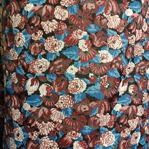 Puede incluir: Primer plano de una tela con un estampado floral. El dise&ntilde;o presenta una mezcla de flores rojas, blancas y rosas, sobre un fondo azul y negro. La tela tiene una impresi&oacute;n densa y completa, creando una apariencia texturizada.