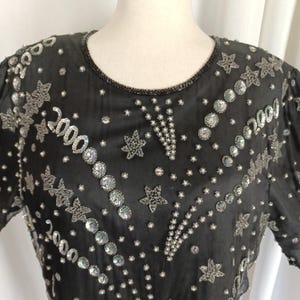 May include: A black sequined top with silver stars and sequins. The top has the year 2000 embroidered on it.