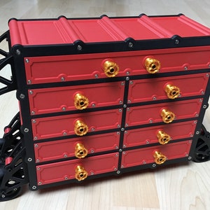 May include: Red toolbox with black trim and gold knobs on wheels. The toolbox has eight drawers.