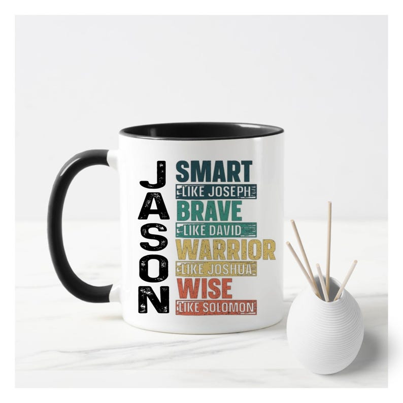 May include: White ceramic mug with a black interior and handle. The mug features the name "JASON" in black vertical text on the side. Below the name are the words "SMART", "BRAVE", "WARRIOR", and "WISE" in colorful text.