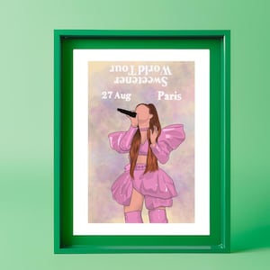 Puede incluir: Un estampado enmarcado con una ilustración estilizada de una cantante con un atuendo rosa y un micrófono. El estampado incluye el texto "Sweetener World Tour" y "Paris, 27 Aug". El marco es verde.