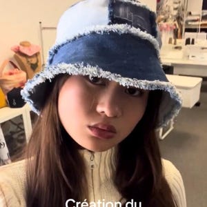 Peut inclure: Bob en jean avec un motif patchwork. Le chapeau a un bord effiloché et une palette de couleurs bleu clair et bleu foncé. Le texte "Création du Bucket Hat Denim" est visible en bas de l'image.