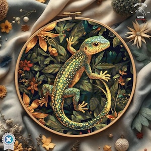 Puede incluir: Un patrón de punto de cruz con un lagarto verde y amarillo con manchas negras, rodeado de exuberante follaje verde y flores amarillas. El patrón se muestra en un aro de bordado redondo.