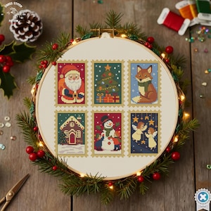 May include: A cross-stitch embroidery hoop featuring six Christmas-themed postage stamp designs. The designs include Santa Claus, a Christmas tree, a fox, a gingerbread house, a snowman, and two angels. The hoop is surrounded by greenery and red berries.