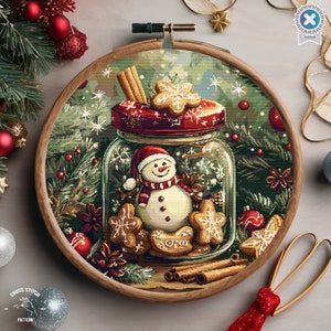 May include: A cross stitch pattern featuring a snowman inside a glass jar with gingerbread cookies, cinnamon sticks, and red berries. The jar has a red lid with a snowflake design. The background is a green forest with snowflakes.
