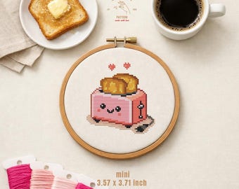 Pode incluir: Um bastidor de bordado em ponto cruz com um design de torradeira rosa, 9,07 x 9,42 cm, com um rosto sorridente e duas fatias de torrada. A imagem também inclui um prato de torradas com manteiga, uma xícara de café e carretéis de linha rosa. O texto diz "CROSS STITCH PATTERN made with love".