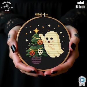 May include: A 5-inch diameter cross-stitch embroidery hoop featuring a Halloween-themed design. The design includes a Christmas tree decorated with pumpkins and a ghost. The background is black, and the hoop is held in hands.