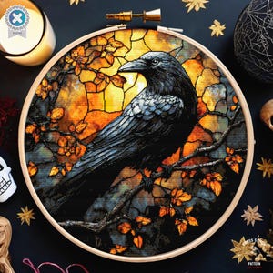Puede incluir: Un patrón de punto de cruz con un cuervo negro posado en una rama con hojas de otoño. El fondo es un diseño de vitral con colores amarillo, naranja y rojo.