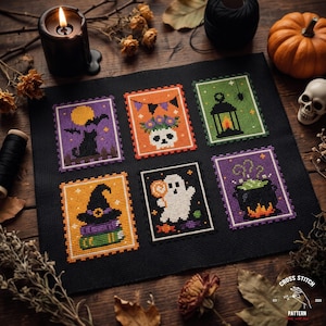 May include: A black fabric piece featuring six rectangular cross-stitch designs arranged in two rows. The motifs include a black cat, a skull with flowers, a lantern, a witch hat on books, a ghost holding a lollipop, and a bubbling cauldron.