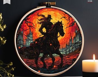 May include: A cross stitch pattern featuring a dark figure riding a horse against a fiery orange and red sunset background. The figure is wearing a hat and cloak, and the horse has glowing eyes. The pattern is framed in a wooden hoop.