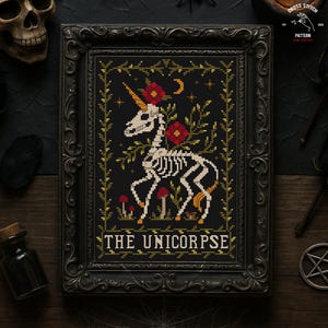 Könnte beinhalten: Kreuzstichmuster eines Skelett-Einhorns mit goldenem Horn, roten Blumen und einem Mond auf schwarzem Hintergrund. Das gerahmte Kunstwerk trägt die Aufschrift "THE UNICORPSE" in weißem Text. Der Rahmen ist verziert und schwarz.