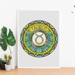 Peut inclure: Mod&egrave;le de point de croix pour une mandala color&eacute;e avec le signe du zodiaque Taureau au centre. La mandala est entour&eacute;e d'une bordure jaune avec le mot "Taureau" &eacute;crit en lettres jaunes.