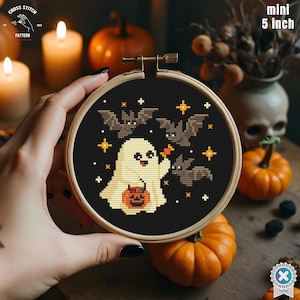 Può includere: Un mini telaio da ricamo da 12,7 cm con un design di Halloween. Il design include un fantasma sorridente, pipistrelli, stelle e una zucca su sfondo nero. Il telaio è tenuto in una cornice di legno.