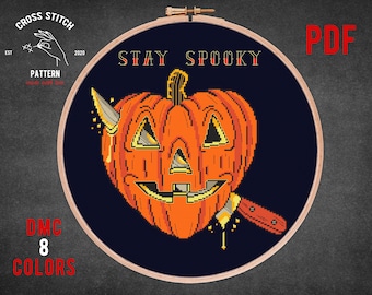 May include: Cross stitch pattern featuring a grinning jack-o'-lantern with a knife, surrounded by the text "Stay Spooky". The pattern is for 8 colors and is available as a PDF download.